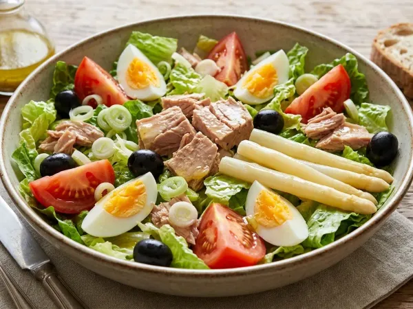 Ensalada mixta en fuente con lechuga, tomate, cebolla, atún, huevo duro y aceitunas